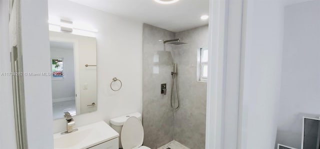 bathroom with vanity, tiled shower, and toilet