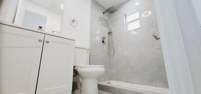 bathroom with a tile shower and toilet