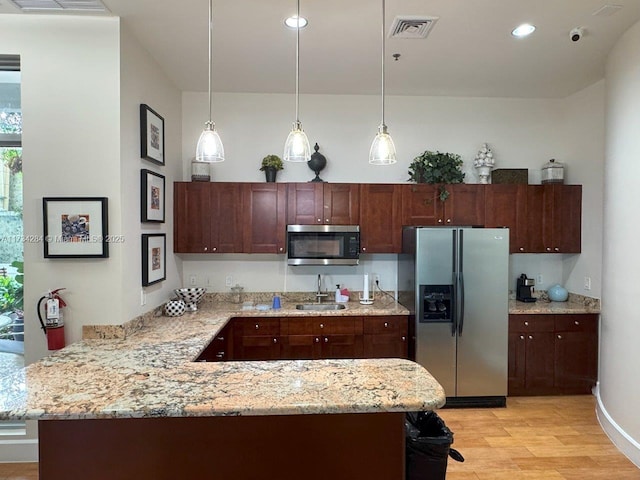 kitchen featuring pendant lighting, sink, kitchen peninsula, and appliances with stainless steel finishes