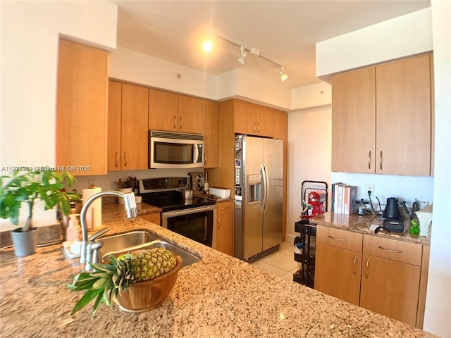 kitchen featuring light tile patterned flooring, rail lighting, sink, stainless steel appliances, and light stone countertops