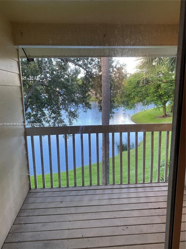 wooden terrace with a water view and a lawn