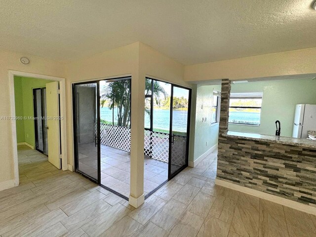 entryway featuring a water view and a textured ceiling