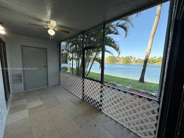 unfurnished sunroom featuring a water view, ceiling fan, and a wealth of natural light