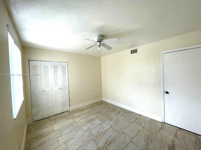 unfurnished bedroom with multiple windows, a textured ceiling, a closet, and ceiling fan