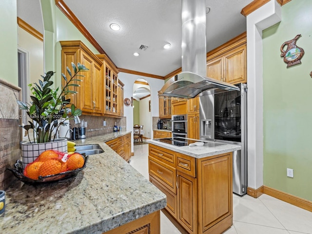 kitchen with island range hood, backsplash, ornamental molding, light tile patterned floors, and light stone counters
