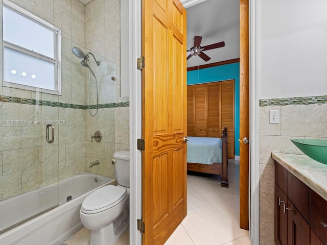 full bathroom with toilet, tile walls, vanity, enclosed tub / shower combo, and tile patterned flooring
