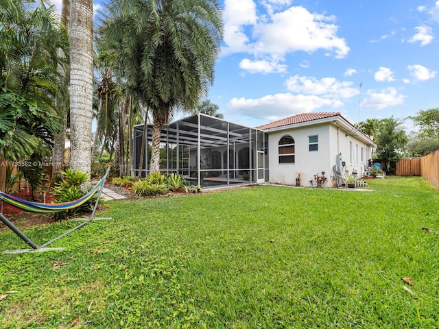 back of house with a lanai and a lawn