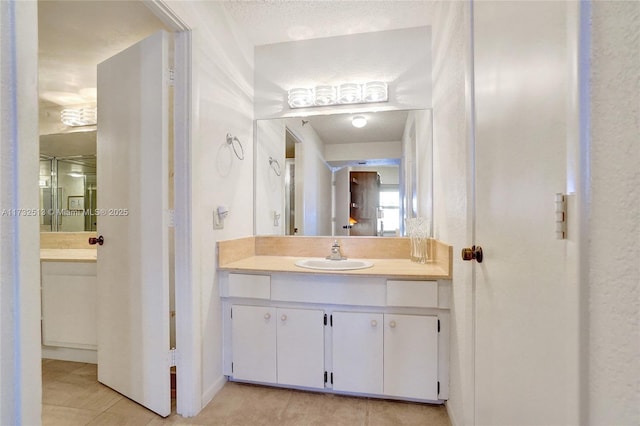 bathroom with tile patterned floors, vanity, and a textured ceiling