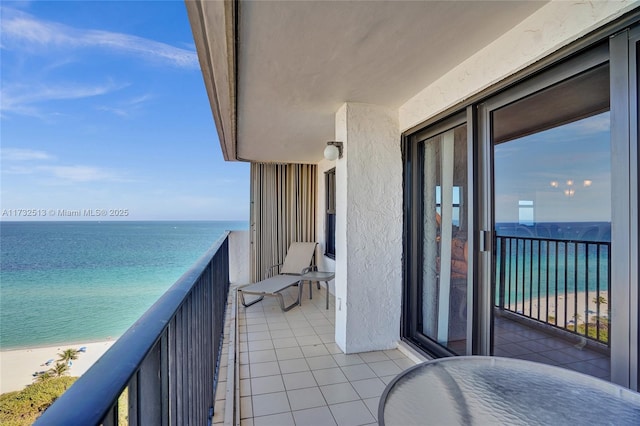 balcony with a water view and a view of the beach