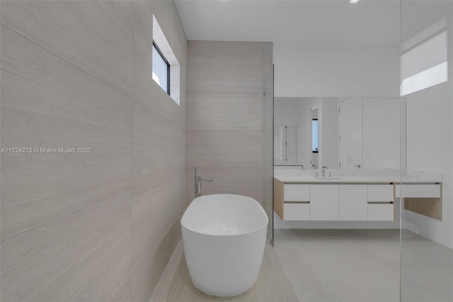 bathroom featuring a washtub, vanity, and tile walls