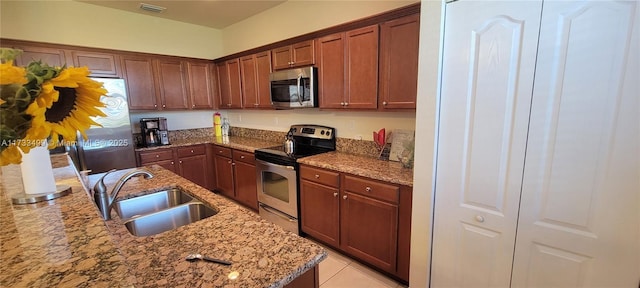 kitchen featuring appliances with stainless steel finishes, sink, light tile patterned floors, and light stone counters