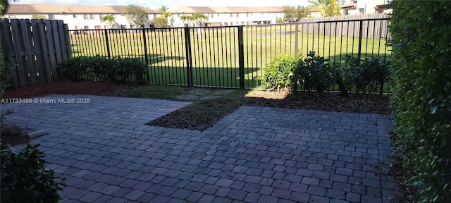 view of gate featuring a patio area and a lawn