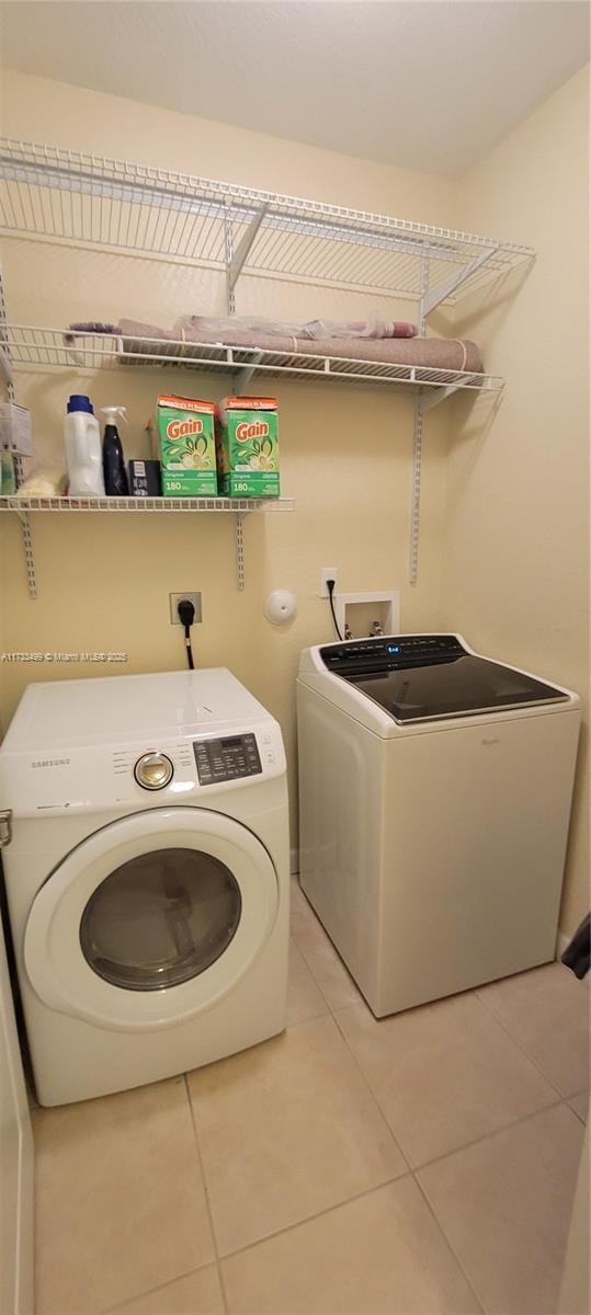 laundry area with light tile patterned floors and washing machine and clothes dryer