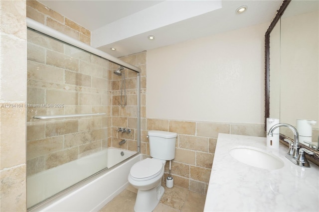 full bathroom with vanity, toilet, combined bath / shower with glass door, and tile walls