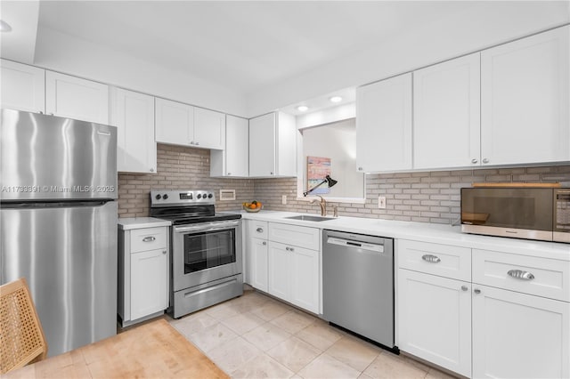 kitchen with tasteful backsplash, white cabinetry, appliances with stainless steel finishes, and sink