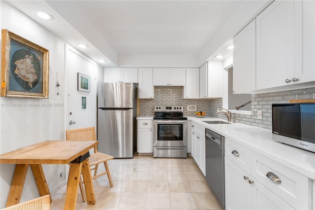 kitchen with sink, appliances with stainless steel finishes, white cabinetry, tasteful backsplash, and light tile patterned flooring