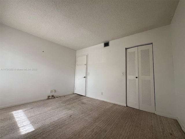 unfurnished bedroom featuring carpet flooring, a textured ceiling, and a closet