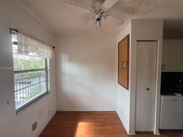 unfurnished dining area featuring ceiling fan, wood-type flooring, and a textured ceiling