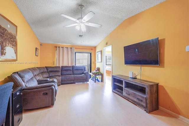 living room featuring ceiling fan, vaulted ceiling, and a textured ceiling