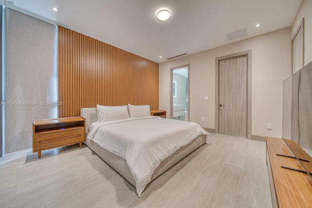 bedroom featuring connected bathroom and light wood-type flooring