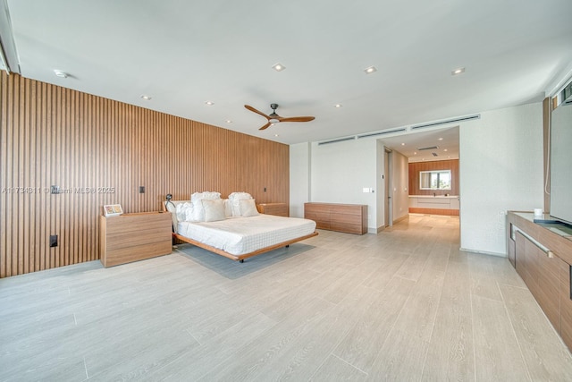 bedroom featuring a barn door, light hardwood / wood-style flooring, and wood walls