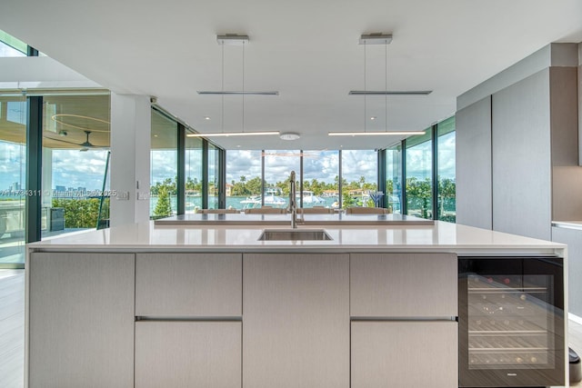 kitchen featuring wine cooler, a spacious island, a healthy amount of sunlight, and sink