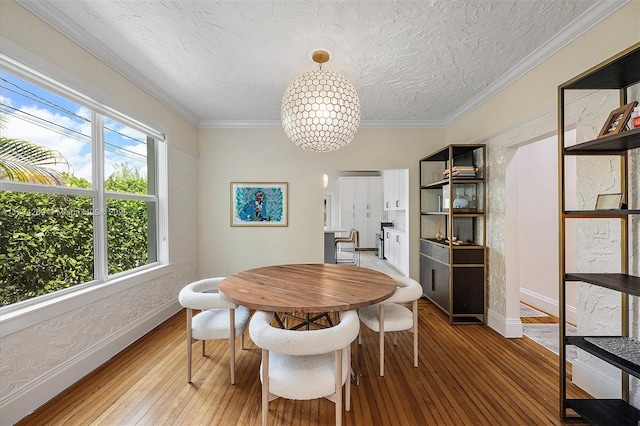 dining room with hardwood / wood-style flooring, ornamental molding, a notable chandelier, and a textured ceiling