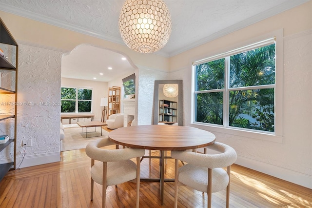 dining room featuring crown molding, plenty of natural light, a textured ceiling, and light wood-type flooring