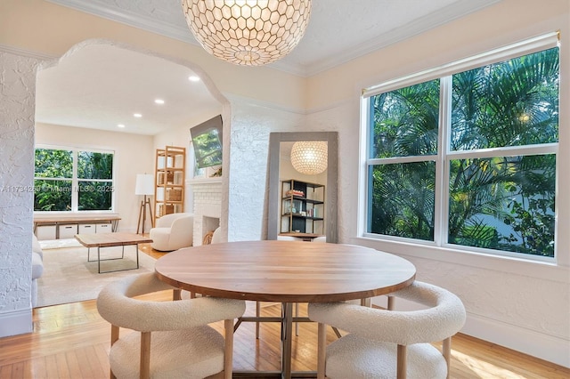 dining space with ornamental molding, light hardwood / wood-style floors, and a brick fireplace