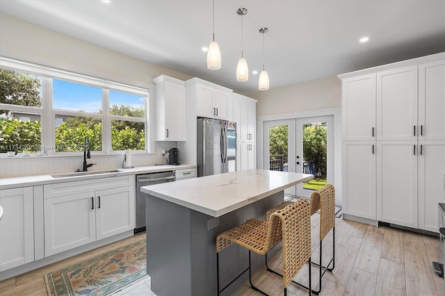 kitchen featuring sink, white cabinetry, appliances with stainless steel finishes, a kitchen breakfast bar, and a kitchen island