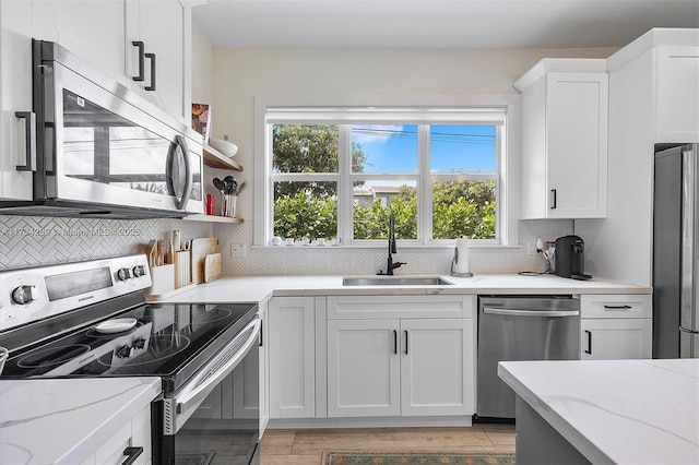 kitchen with sink, stainless steel appliances, white cabinets, and light stone countertops