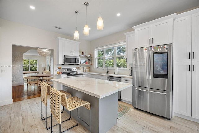 kitchen with white cabinetry, light stone countertops, stainless steel appliances, and a center island