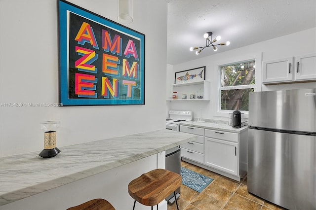 kitchen with a breakfast bar area, light stone counters, white cabinets, and stainless steel refrigerator