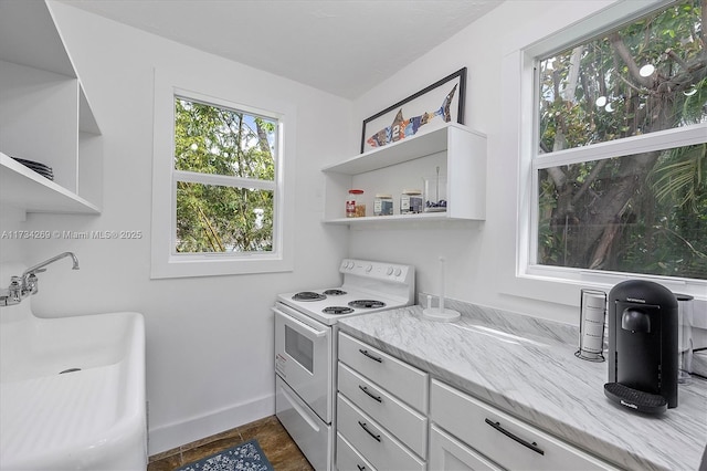 kitchen featuring sink, white electric range oven, white cabinets, and light stone counters