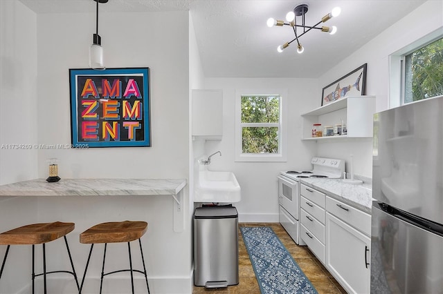 kitchen featuring sink, stainless steel refrigerator, light stone countertops, white cabinets, and white electric stove