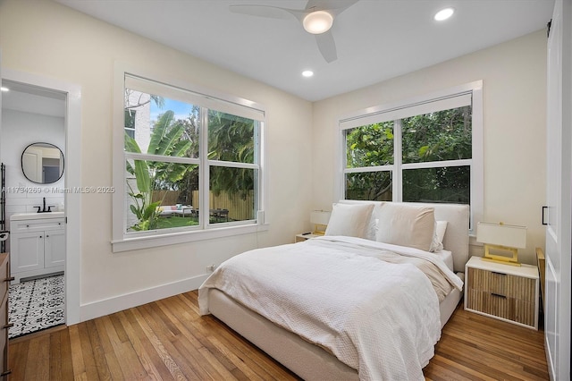 bedroom featuring sink, ensuite bath, light hardwood / wood-style flooring, radiator heating unit, and ceiling fan