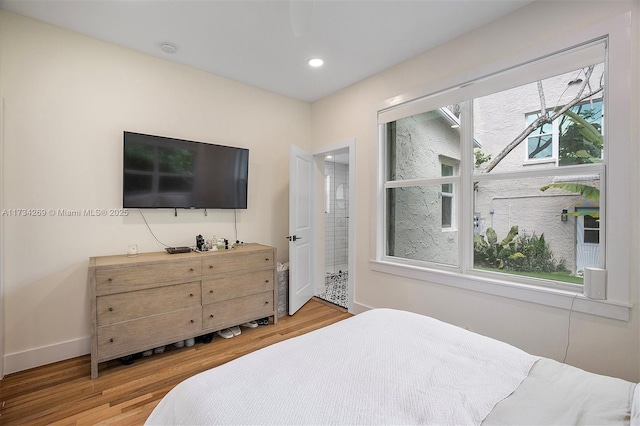 bedroom with multiple windows, hardwood / wood-style floors, and ensuite bathroom