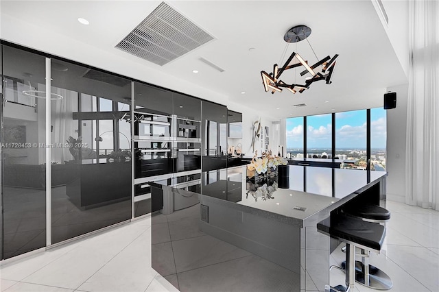 kitchen featuring a spacious island, light tile patterned flooring, expansive windows, and decorative light fixtures