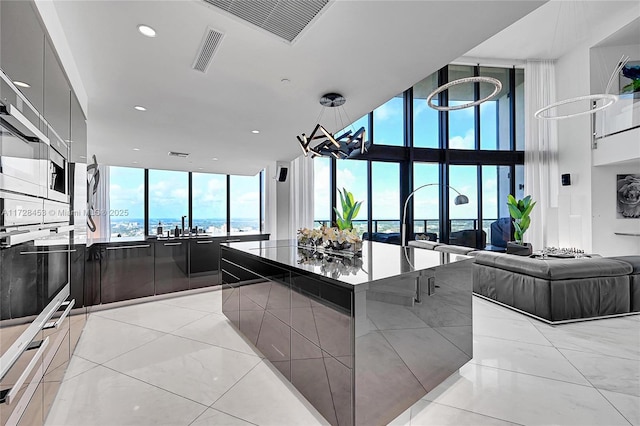 kitchen featuring a large island, floor to ceiling windows, stainless steel oven, a water view, and light tile patterned flooring