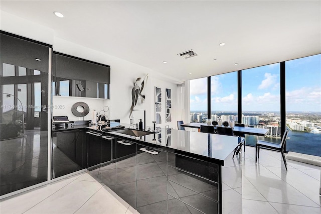 kitchen featuring a water view, light tile patterned flooring, sink, and a wall of windows