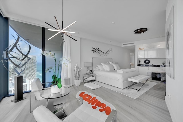 bedroom featuring light hardwood / wood-style floors, an inviting chandelier, and a wall of windows