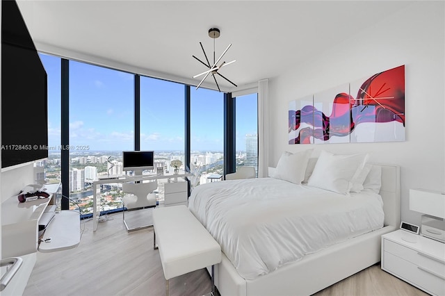 bedroom with a wall of windows, a chandelier, and wood-type flooring