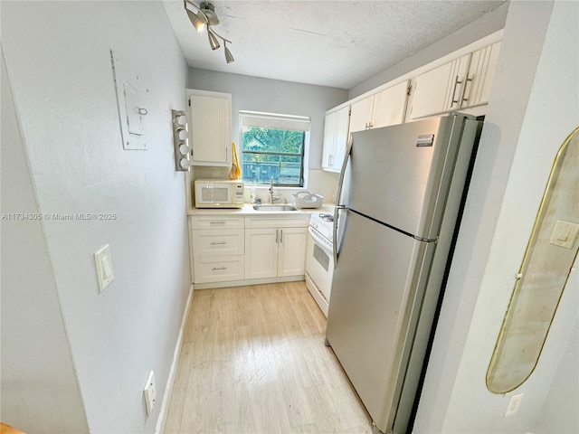 kitchen featuring white cabinetry, sink, white appliances, a textured ceiling, and light wood-type flooring