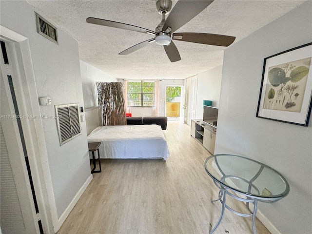 bedroom featuring ceiling fan, light hardwood / wood-style flooring, and a textured ceiling