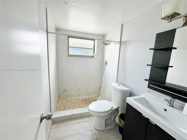 bathroom featuring vanity, tiled shower, and toilet