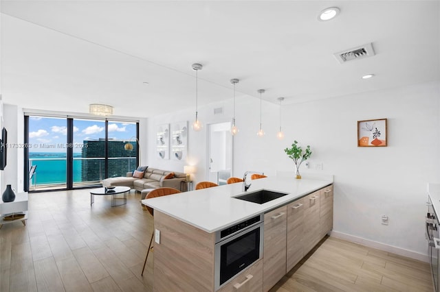 kitchen featuring decorative light fixtures, sink, a breakfast bar area, kitchen peninsula, and a water view