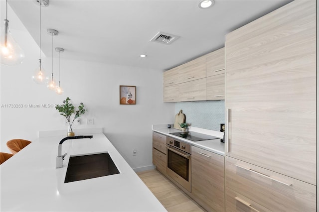 kitchen featuring sink, tasteful backsplash, black electric stovetop, decorative light fixtures, and stainless steel oven