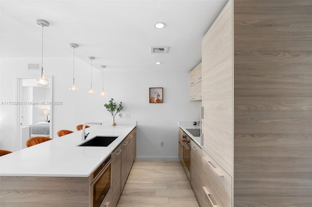 kitchen featuring sink, decorative light fixtures, stainless steel microwave, kitchen peninsula, and black electric stovetop