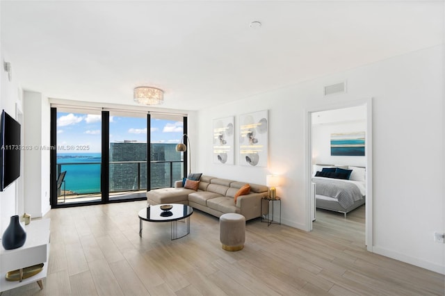 living room featuring floor to ceiling windows, a water view, and light hardwood / wood-style floors