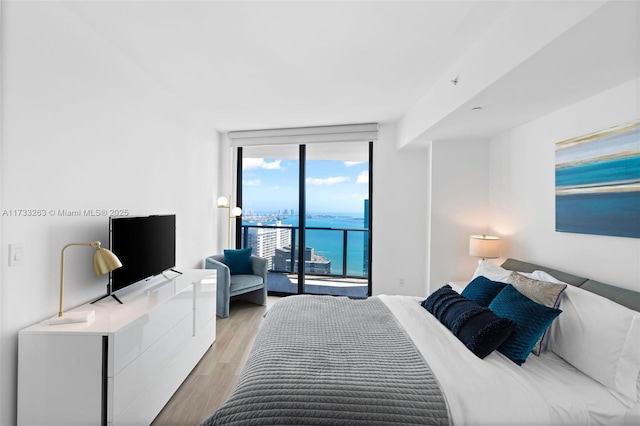 bedroom with expansive windows, access to exterior, and light wood-type flooring